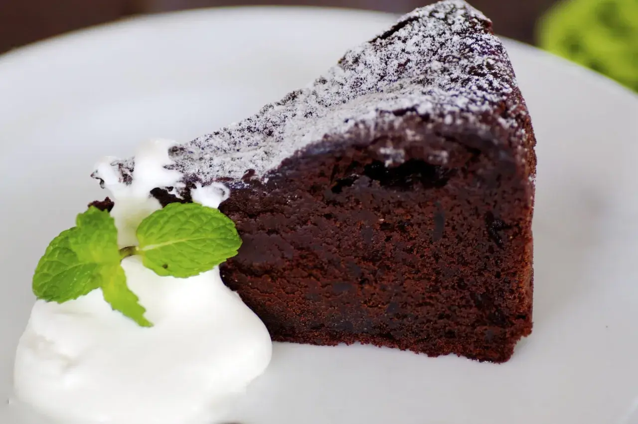 Un trozo de bizcocho de chocolate esponjoso con yogur y menta, espolvoreado con azúcar glas.