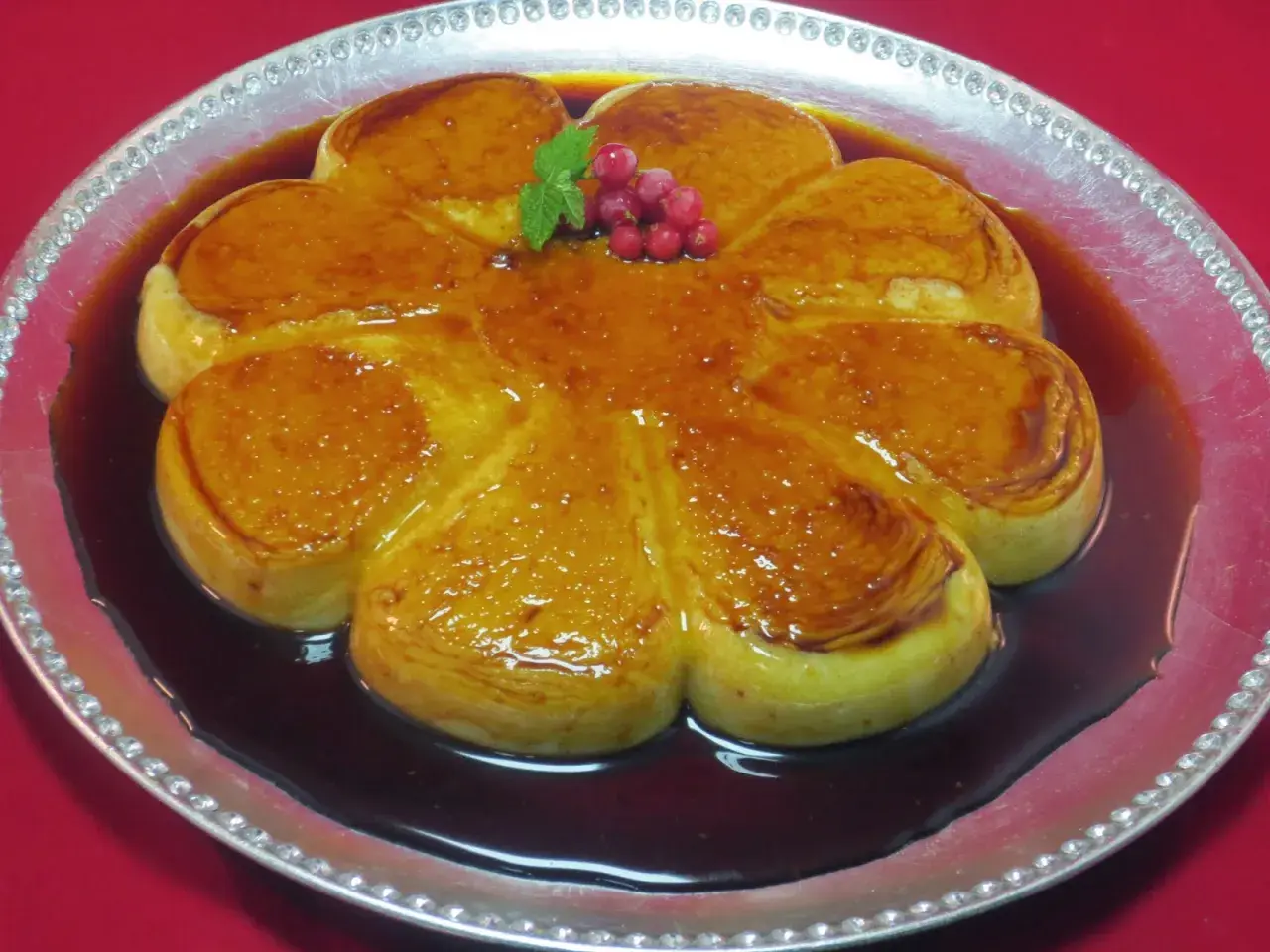 Delicioso flan de arroz con leche con caramelo dorado, decorado con bayas rojas y menta.