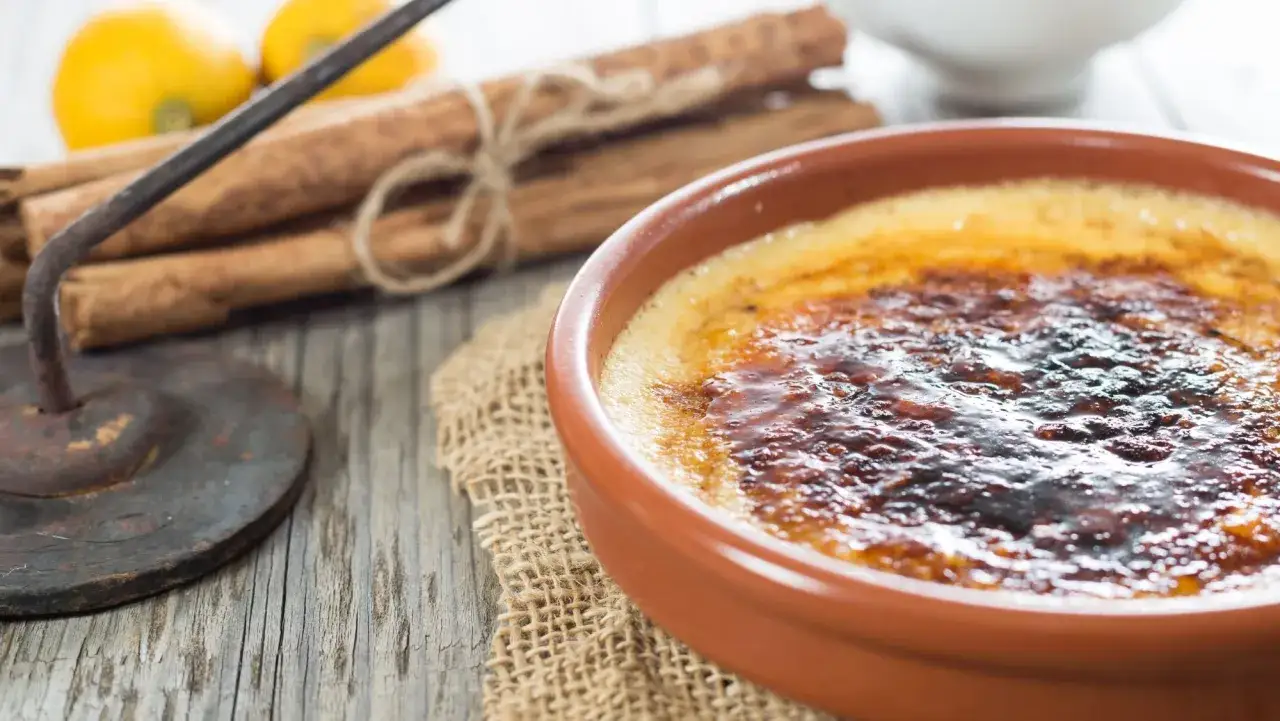 Crema catalana con una capa crujiente de caramelo, junto a canela y limones.