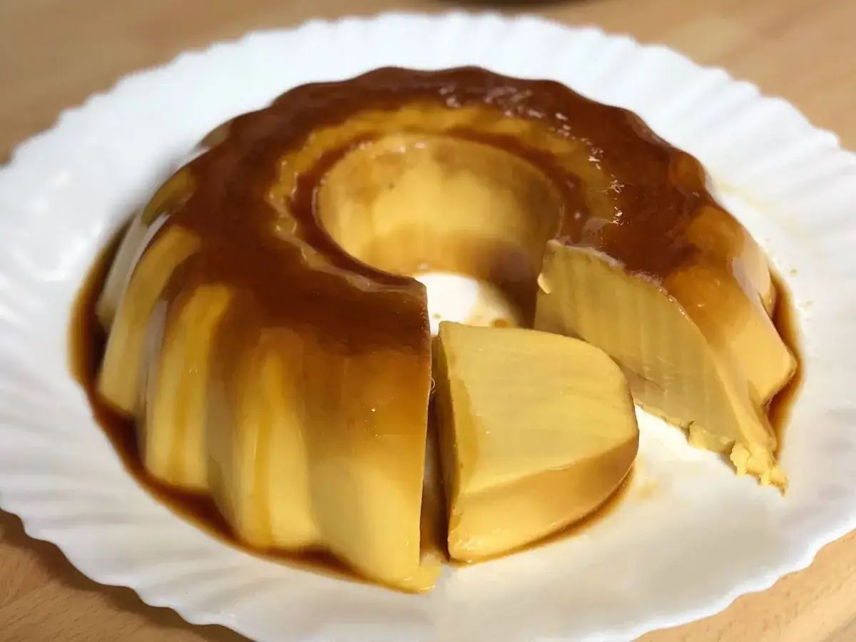Delicioso flan de chocolate blanco con caramelo l&iacute;quido, servido en un plato blanco.