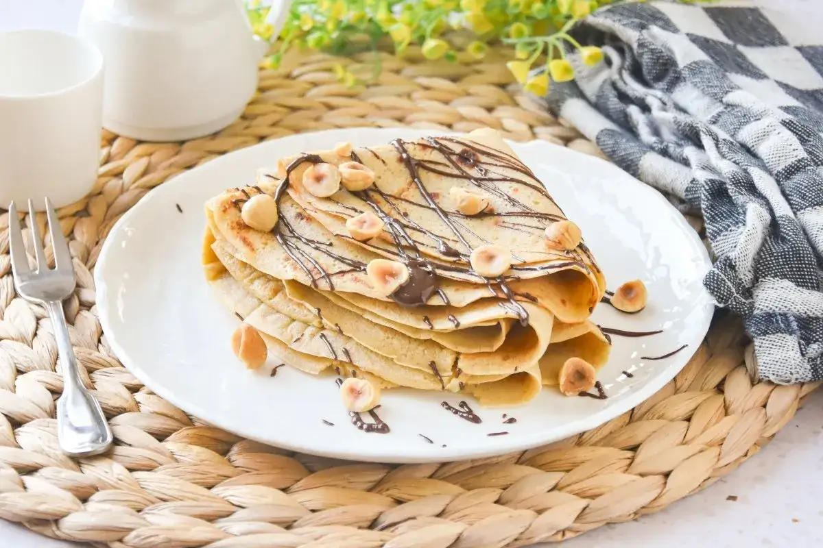 Deliciosos crepes de avena cubiertos con chocolate y avellanas, listos para disfrutar.