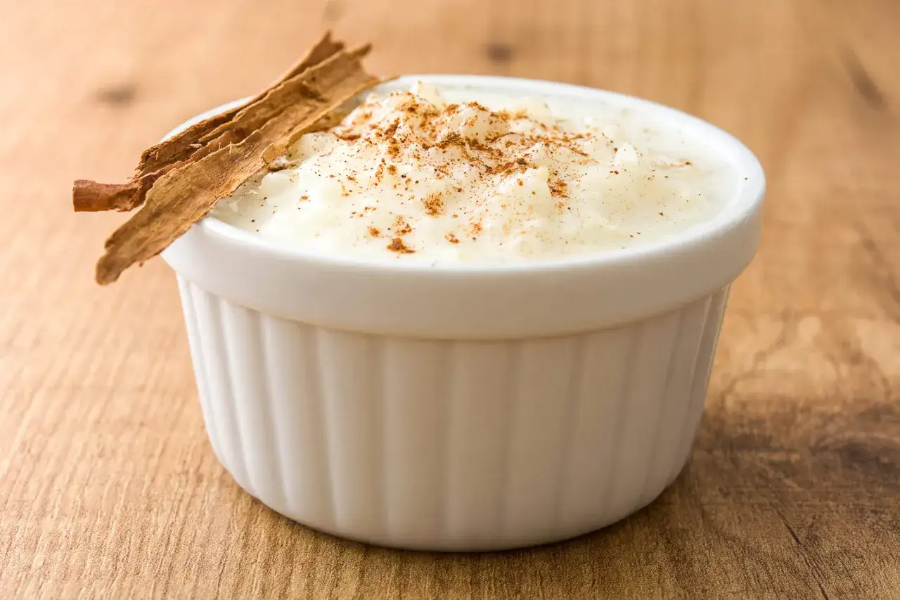Delicioso arroz con leche cremoso, espolvoreado con canela y decorado con una rama de canela. Una receta perfecta para disfrutar.