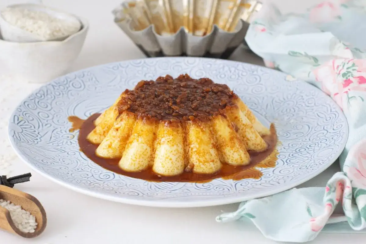 Delicioso flan de arroz con leche, con caramelo dorado y un toque de canela. Servido en plato decorado.