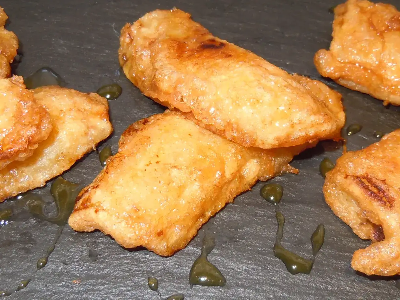 Pl&aacute;tanos fritos dorados y crujientes, ba&ntilde;ados en un sirope oscuro, listos para disfrutar.