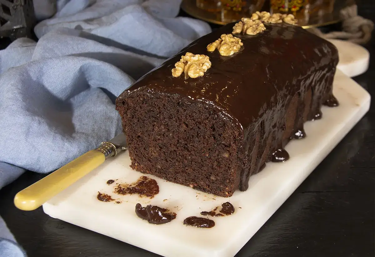 Deliciosa coca de chocolate casera, cubierta con glaseado brillante y nueces. Perfecta para compartir.