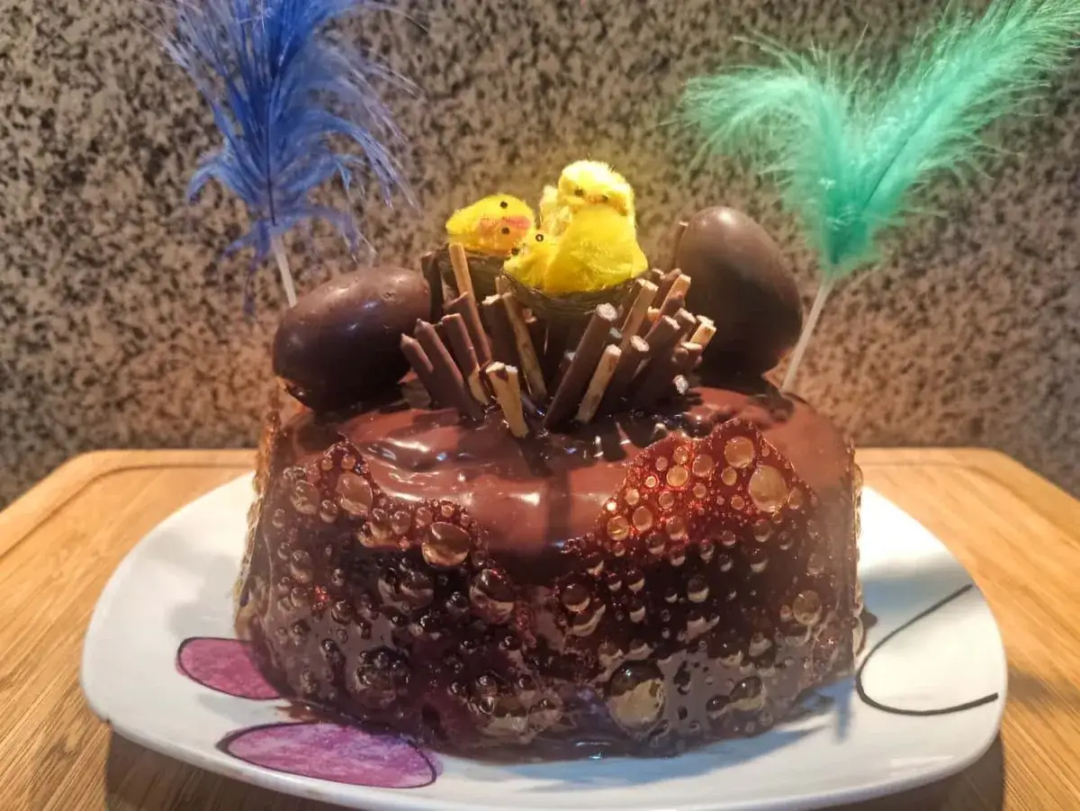 Deliciosa tarta de chocolate, perfecta para una receta mona de pascua. Decorada con huevos de chocolate, pollitos y plumas.