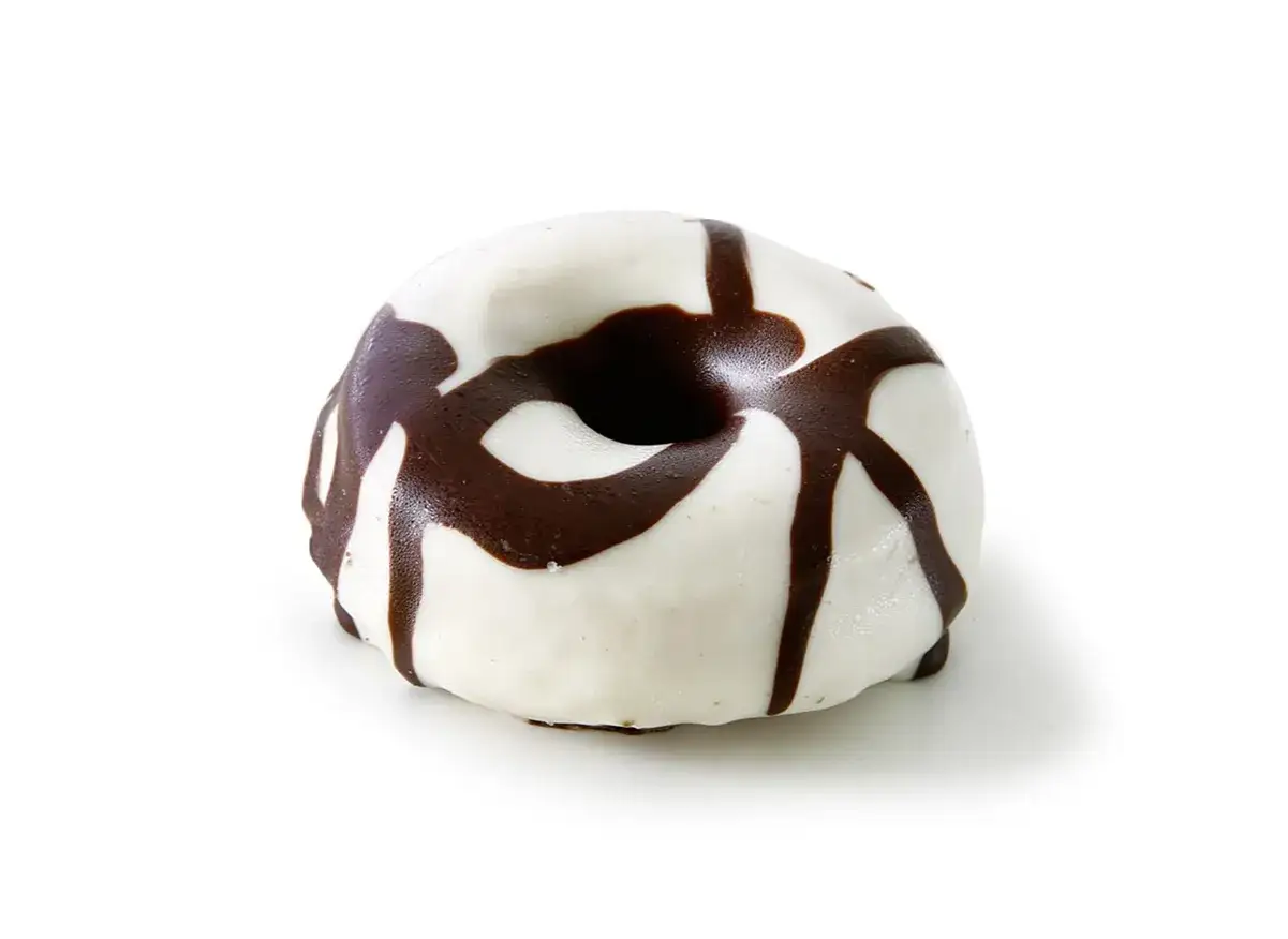 Un delicioso donut de chocolate blanco con un glaseado blanco y un diseño de chocolate negro que cae en cascada.
