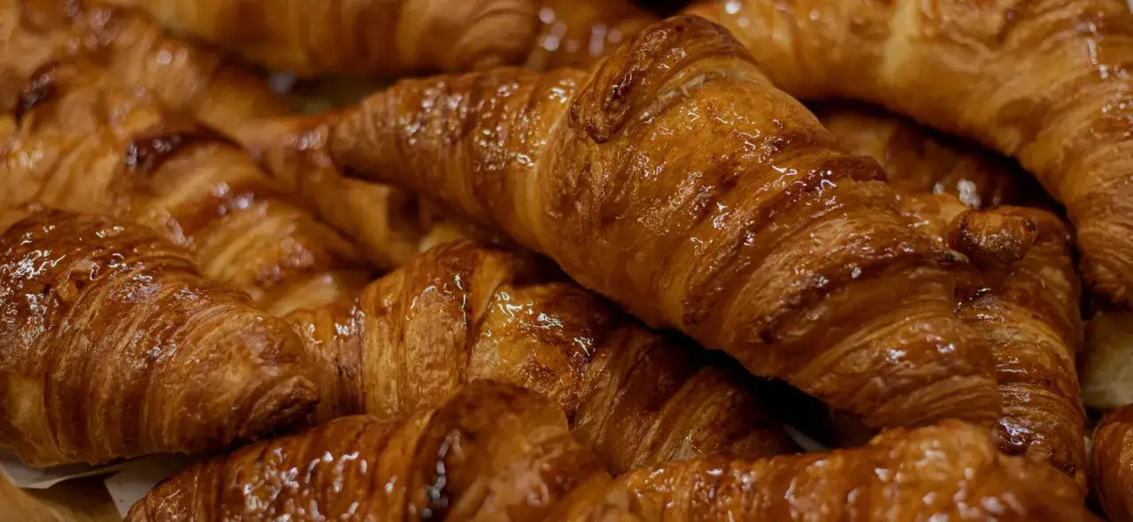 Un mont&oacute;n de croissants dorados y brillantes, un delicioso pan dulce perfecto para el desayuno.