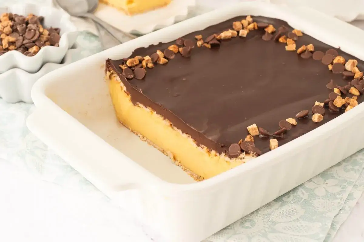 Tarta de galletas de la abuela de toda la vida, con capa de crema amarilla y cobertura de chocolate, decorada con trocitos de galleta y chocolate.
