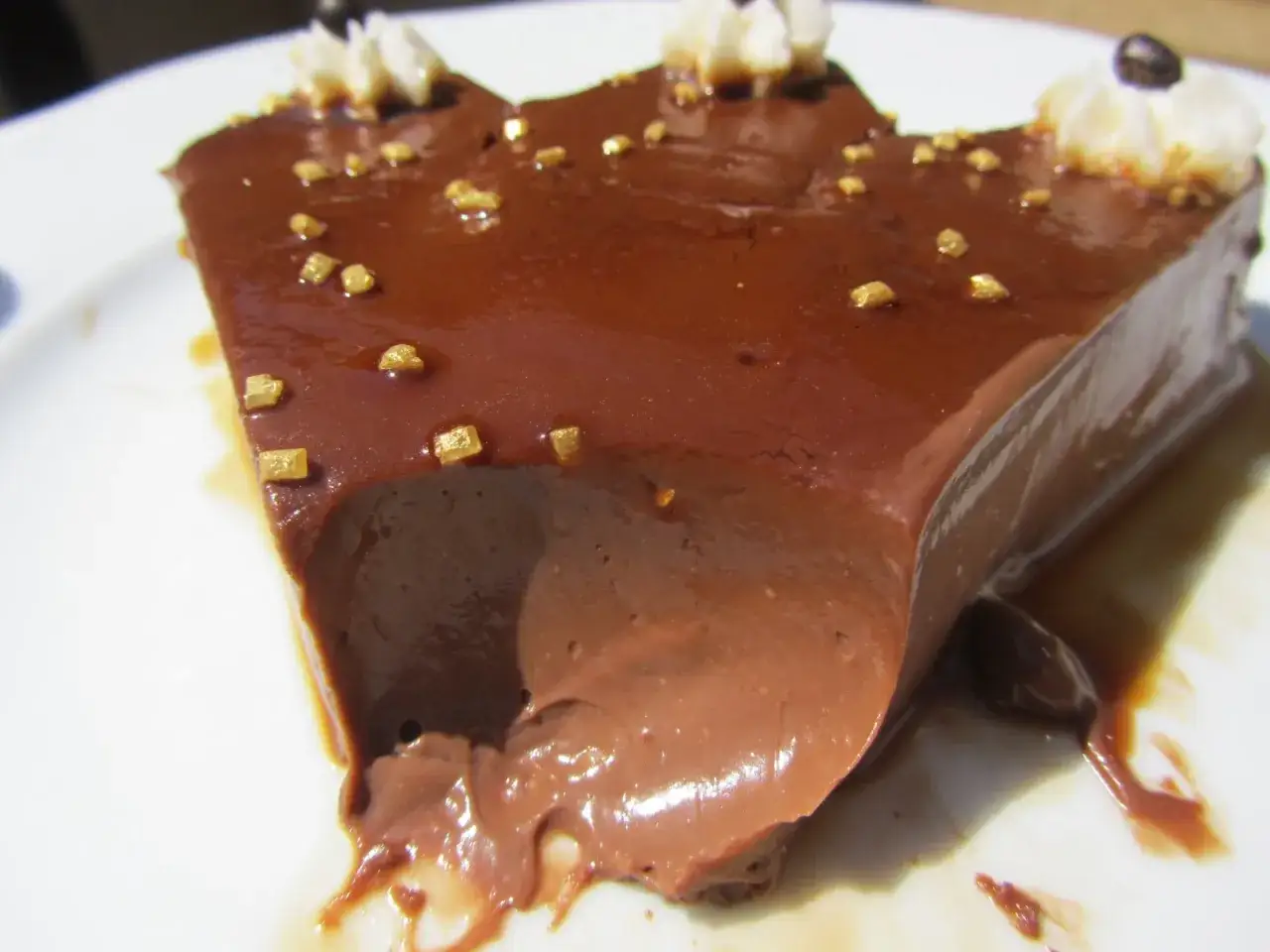 Delicioso flan de chocolate Thermomix, cubierto con caramelo y adornado con virutas doradas y nata.