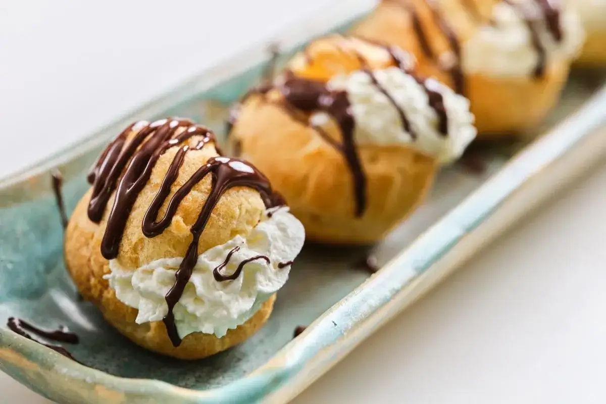 Deliciosos profiteroles de nata, cubiertos con chocolate derretido, listos para ser disfrutados.