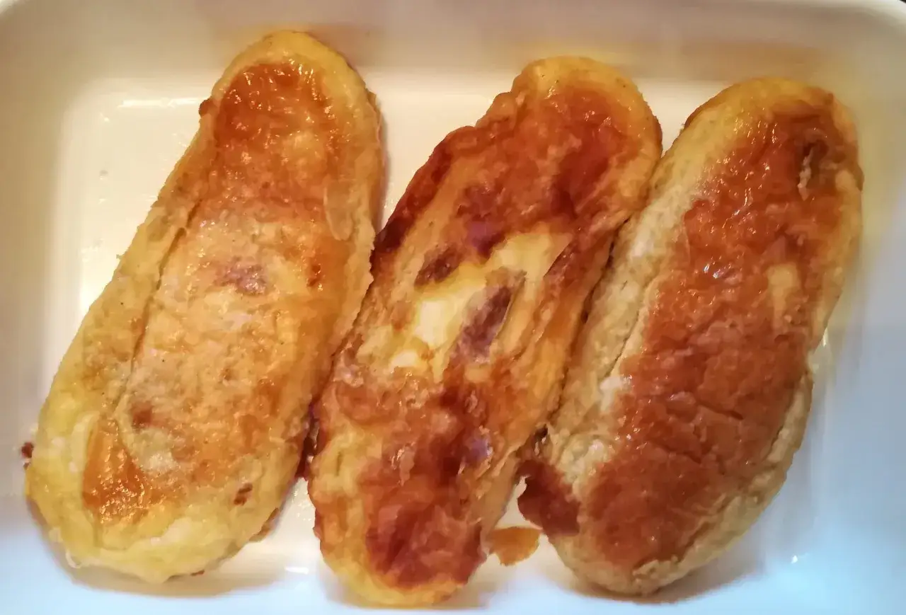 Tres torrijas de horchata doradas y jugosas en una bandeja blanca, listas para disfrutar.