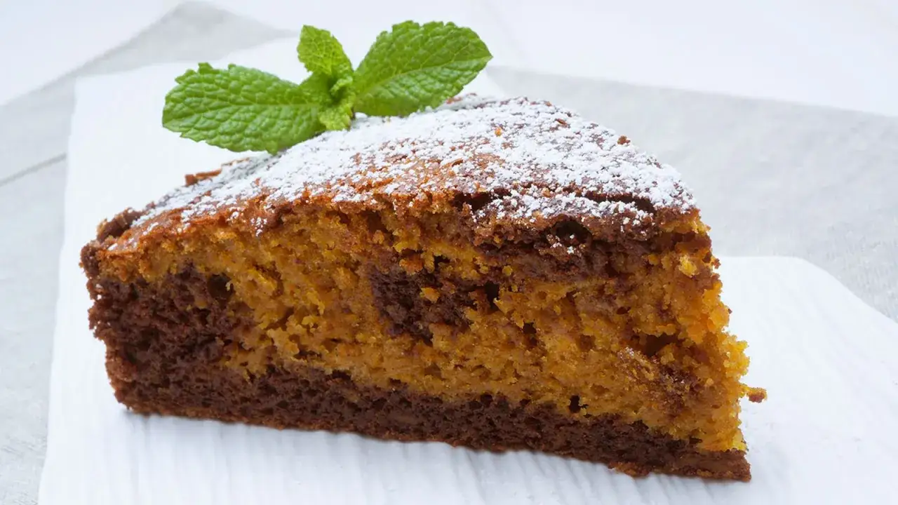 Rebanada de tarta de calabaza y chocolate con az&uacute;car glas y una hoja de menta.