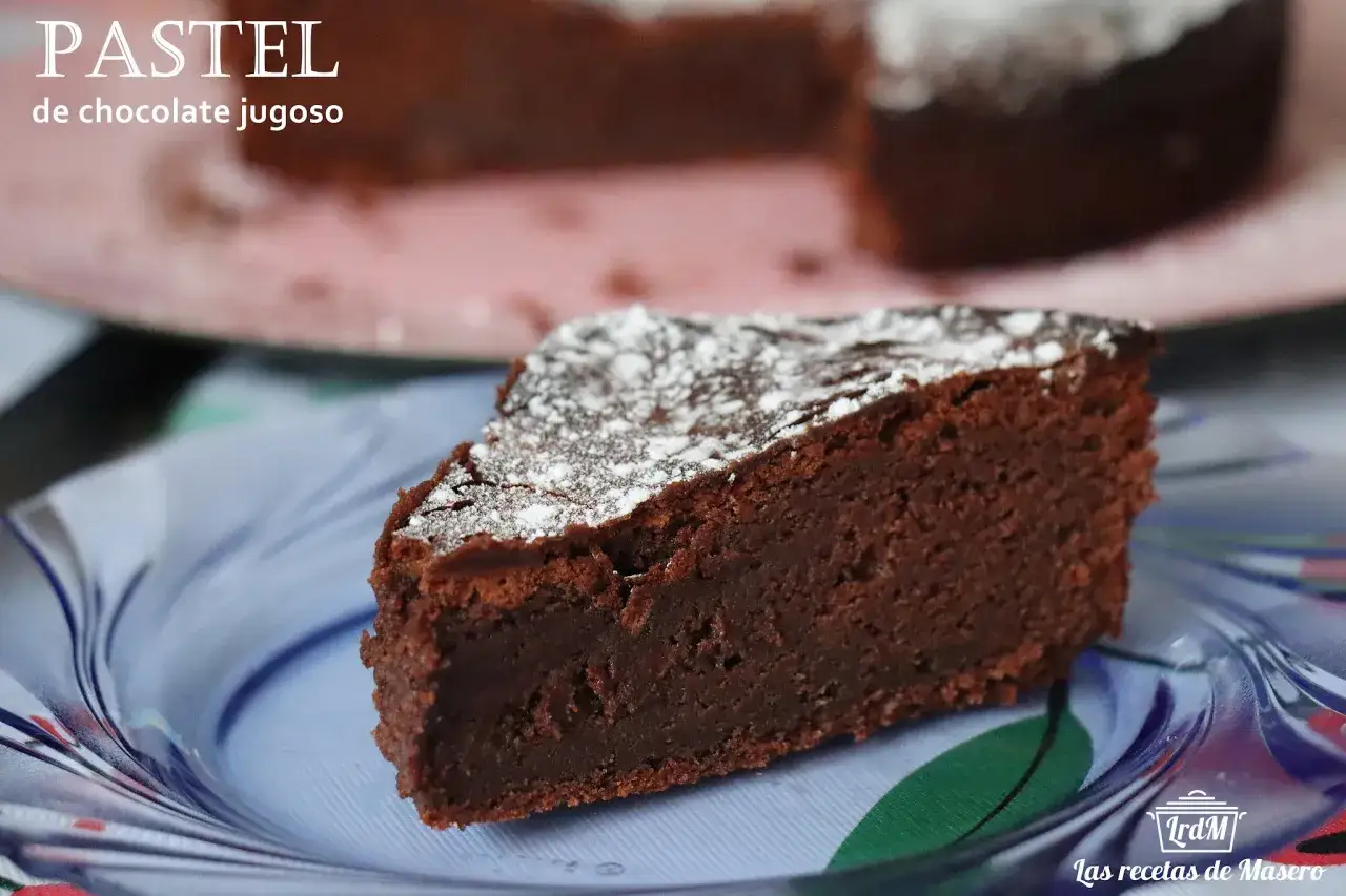 Un trozo de pastel de chocolate jugoso, espolvoreado con az&uacute;car glas, servido en un plato azul.