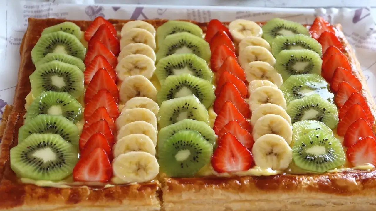 Tarta de hojaldre cubierta con rodajas de kiwi, fresas y pl&aacute;tano, una delicia frutal.