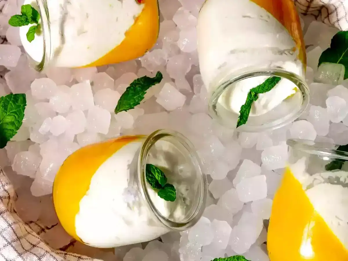 Delicioso mousse de coco en vasitos, servido sobre hielo picado y decorado con hojas de menta fresca.