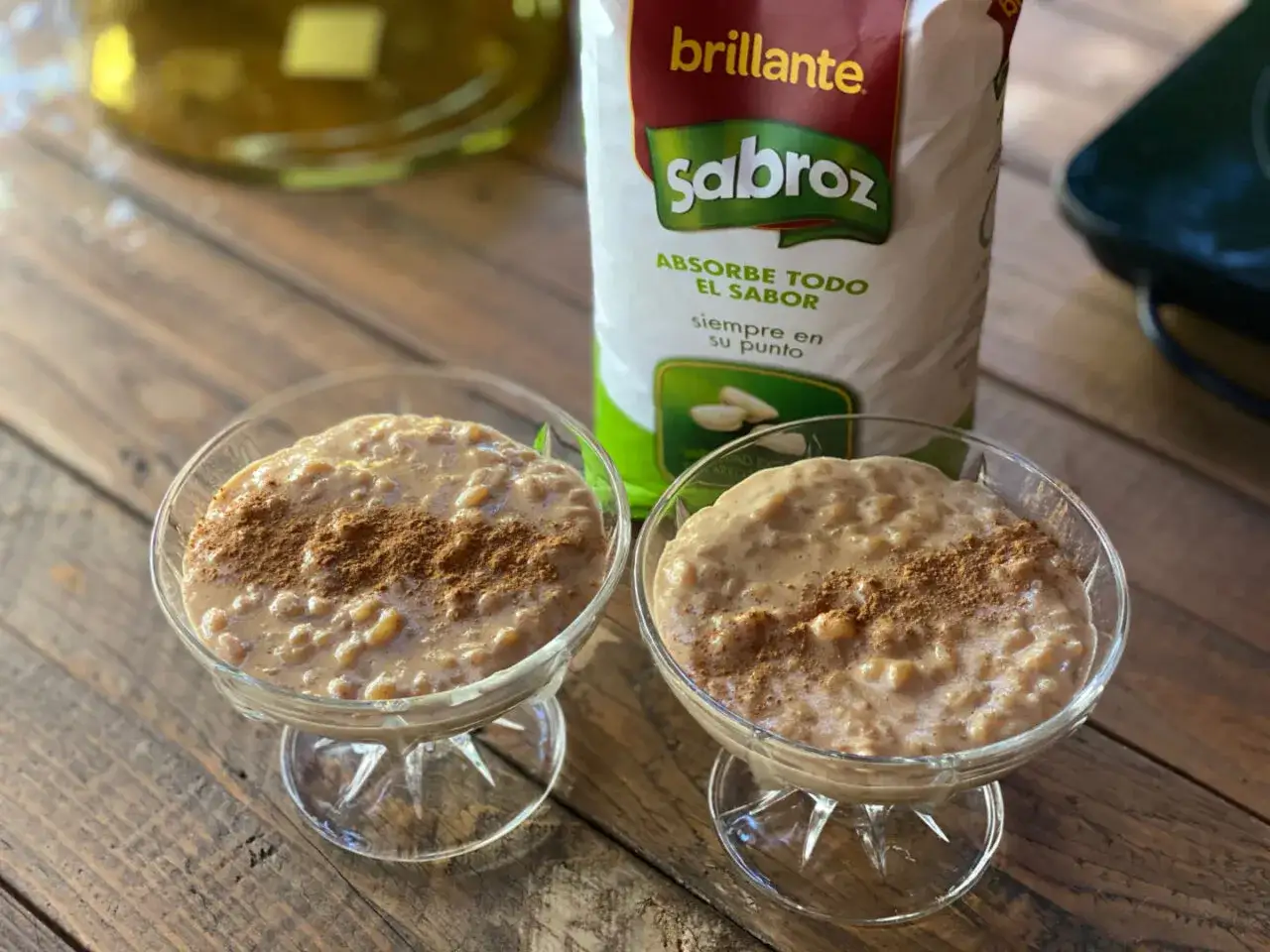 Dos copas de cremoso arroz con leche condensada, espolvoreado con canela. Detrás, una bolsa de arroz Sabroz.
