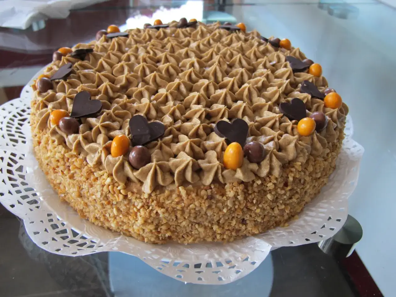 Deliciosa tarta de moka, cubierta con crema de caf&eacute;, almendras y decorada con corazones de chocolate y bolitas.