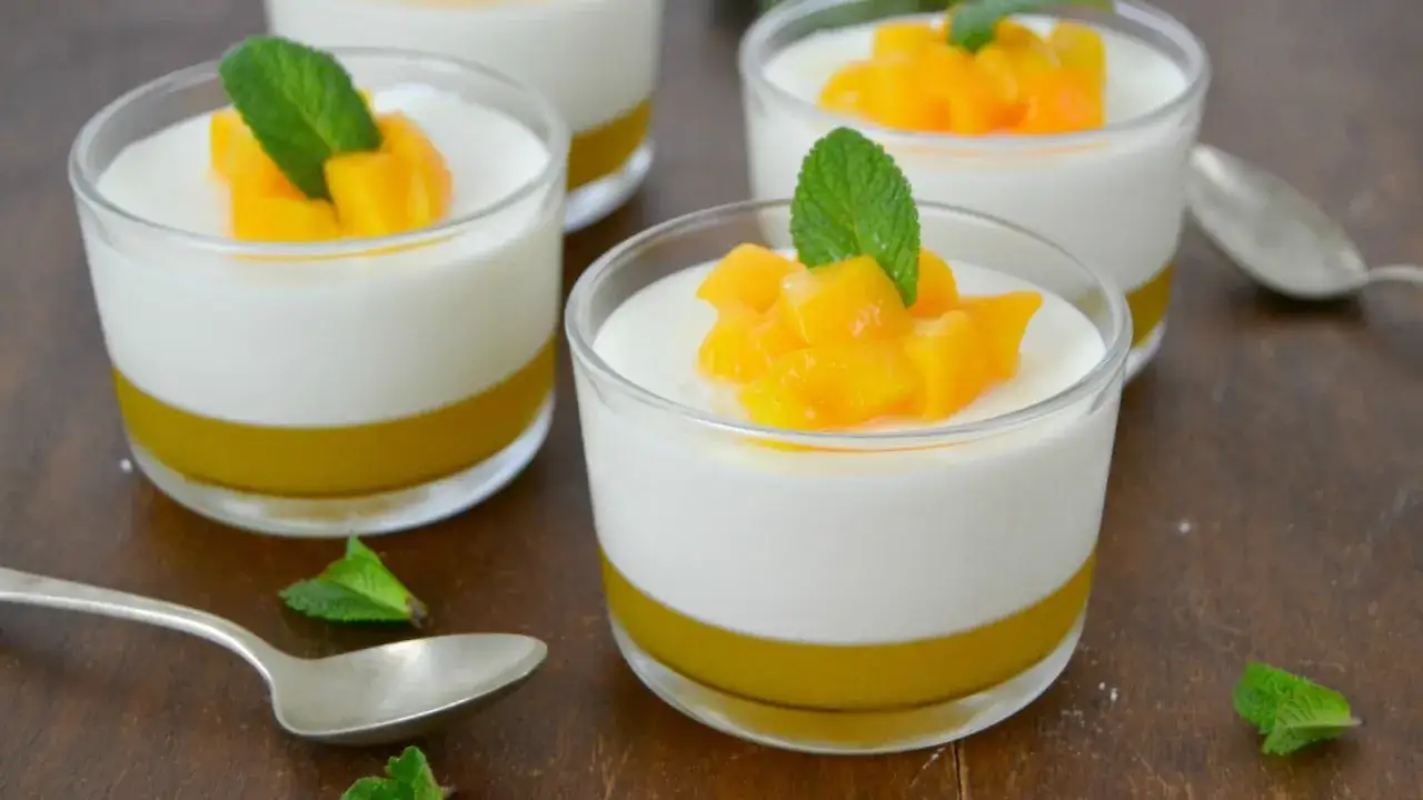Delicioso mousse de melocotón en vasitos de cristal, coronado con trozos de fruta y hojas de menta.