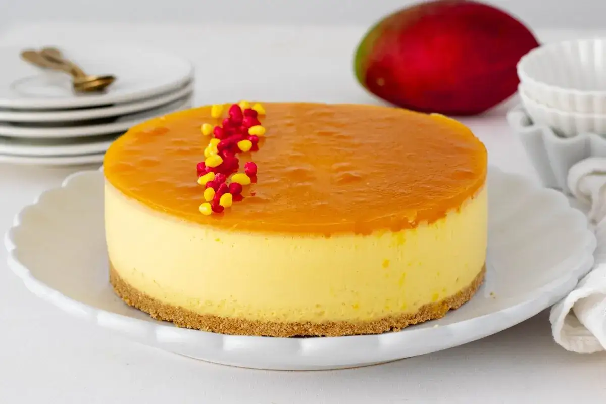 Deliciosa tarta de mango con cobertura brillante y decorada con granos rojos y amarillos. &iexcl;Un postre tropical irresistible!