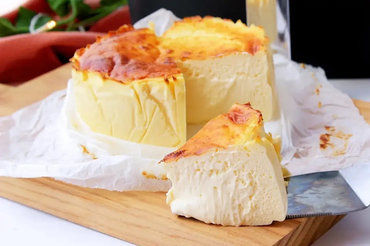 Tarta de queso en freidora de aire, dorada y cremosa, con una porci&oacute;n lista para disfrutar.